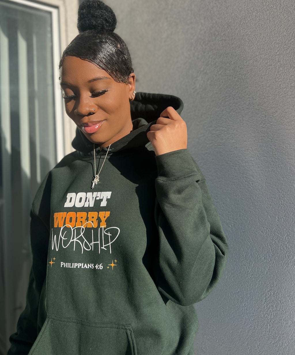 girl wearing Christian streetwear hoodie in green featuring the Don't Worry Worship minimalist design for a modern faith-based look